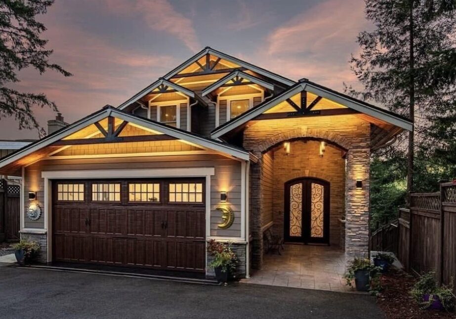 Illuminated modern house with wooden garage door.